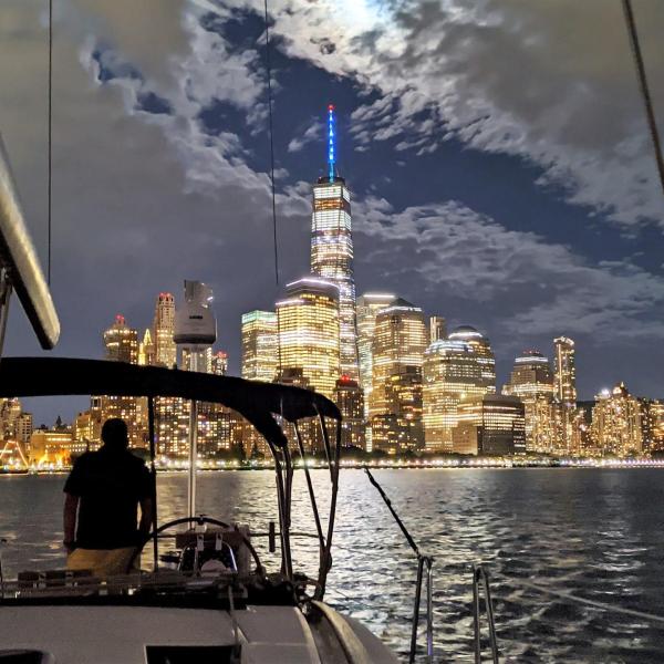 sailboat during an evening cruise NYC with the shining skyscrapers and full moon
