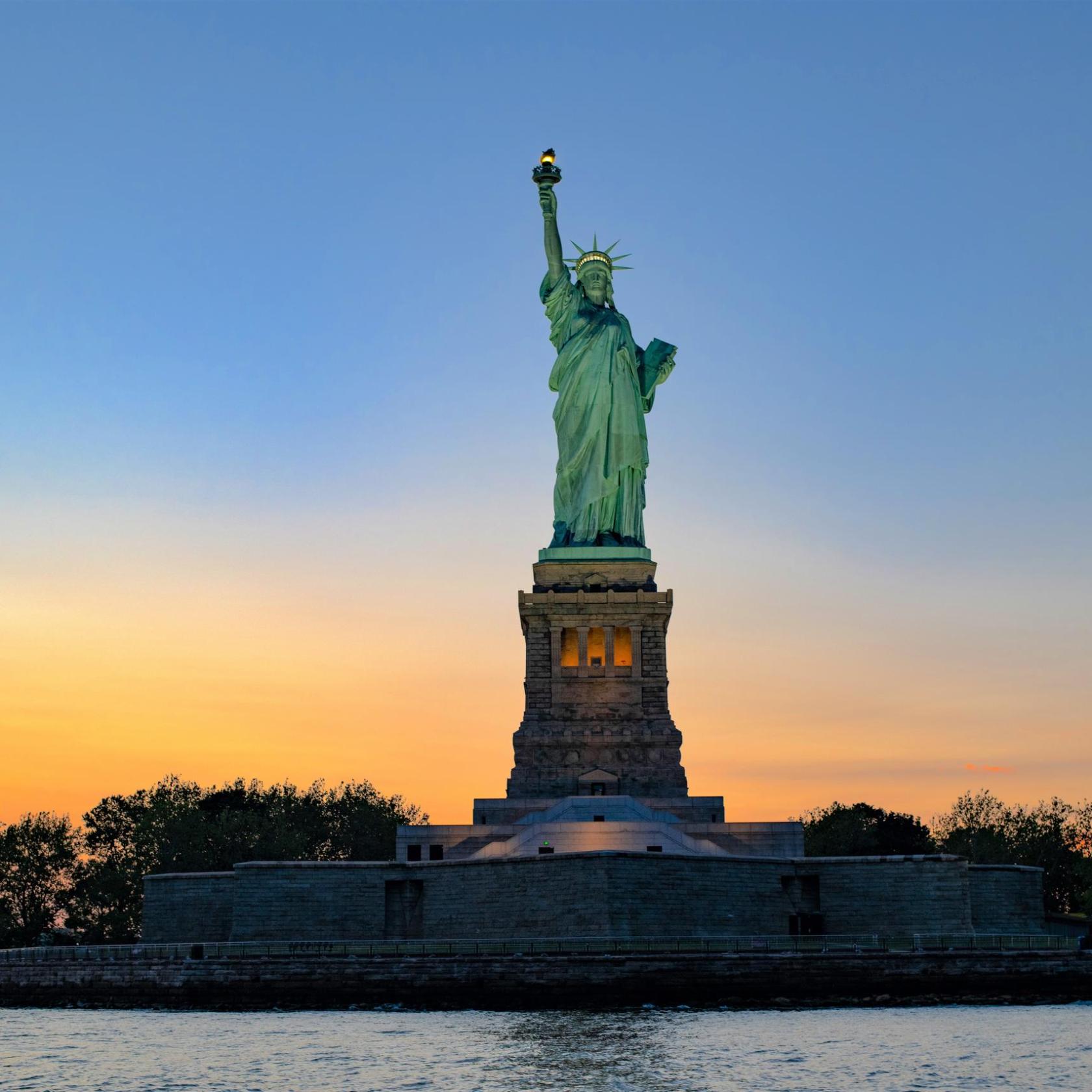 New York sunset cruise with an orange and blue sky behind the Statue of Liberty