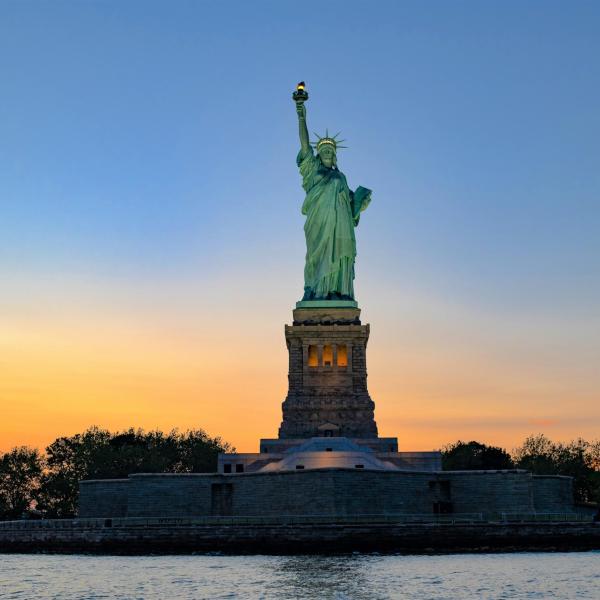 New York sunset cruise with an orange and blue sky behind the Statue of Liberty
