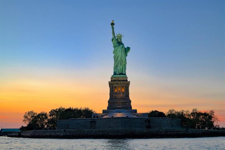 New York sunset cruise with an orange and blue sky behind the Statue of Liberty