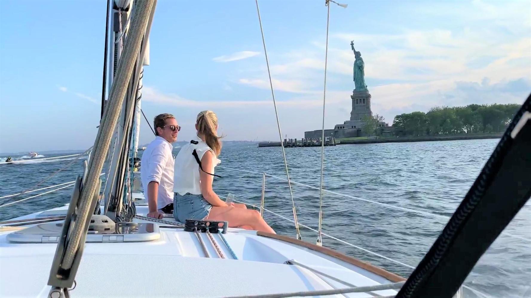 couple sitting on deck sailing towards the Statue of Liberty during a Manhattan sailboat tour 