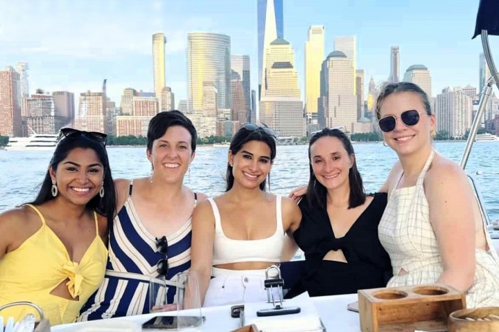 women on a boat ride NYC with dinner and the NYC skyline and One World Trade Center in the background during a boat rent NYC