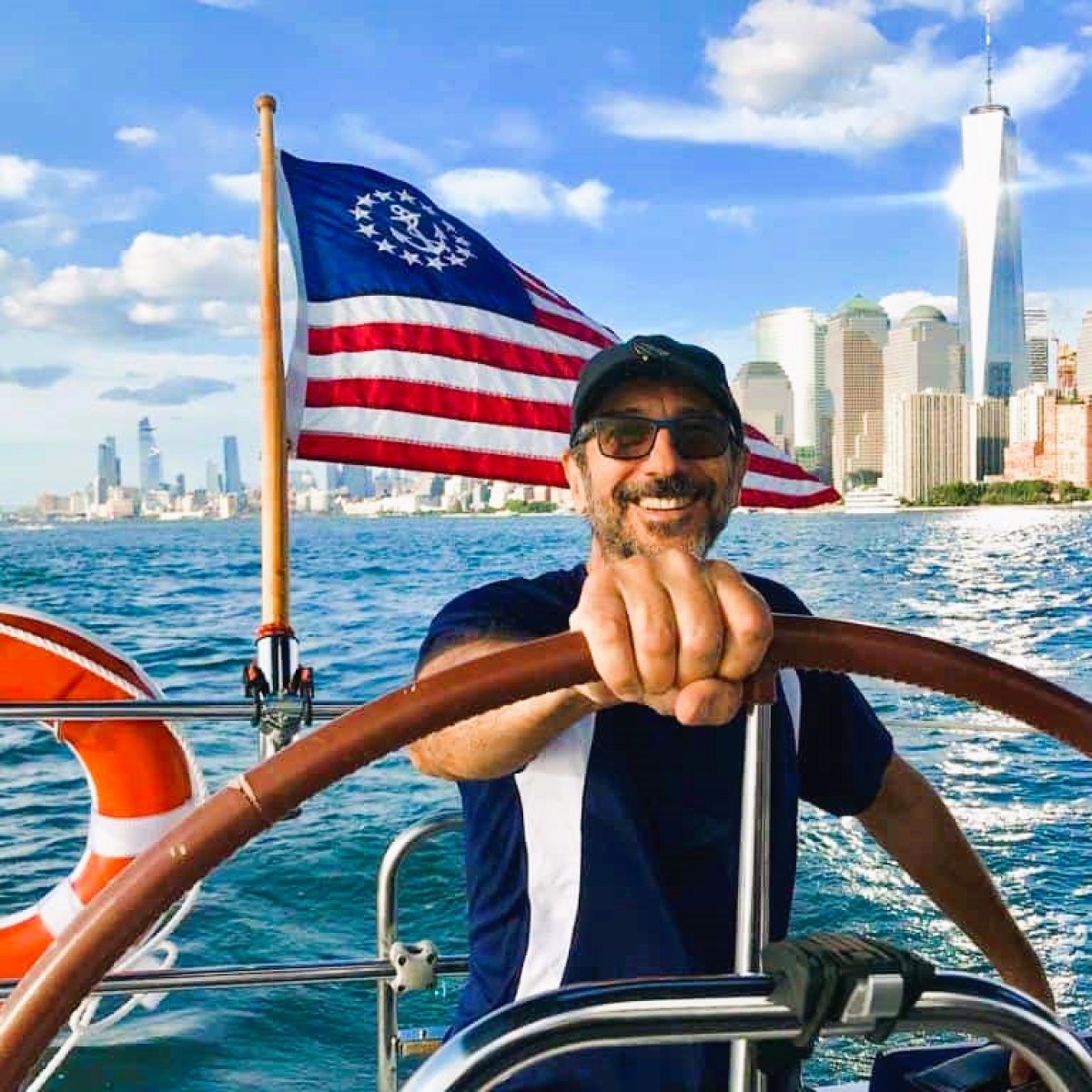 boat rental with captain and his hand on the wheel with American flag and Manhattan skyline