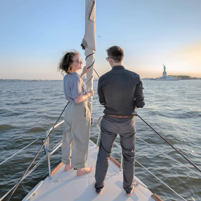 woman and man stand on the deck during a private boat ride in NYC as they sail to the Statue of Liberty