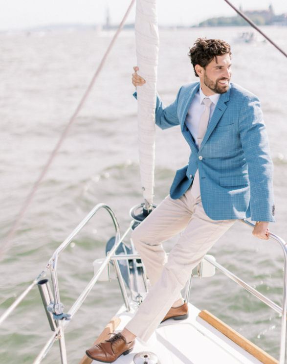 man in a blue jacket at the bow of a boat while sailing New York