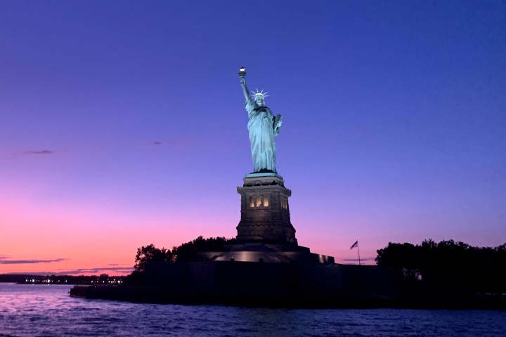 purple and pink sky behind the Statue of Liberty during a sunset cruise NYC private
