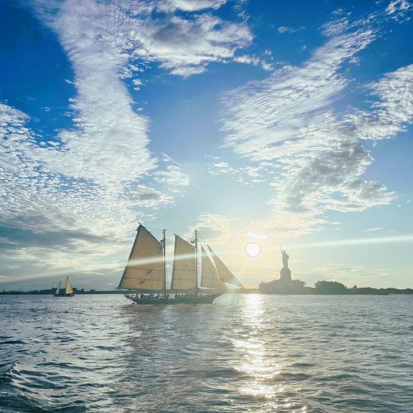 sailboat sailing past the Statue of Liberty during a sunset sail in NYC