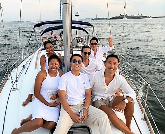 a group of people on a boat posing for the camera on a sailboat during a lunch cruise in NYC