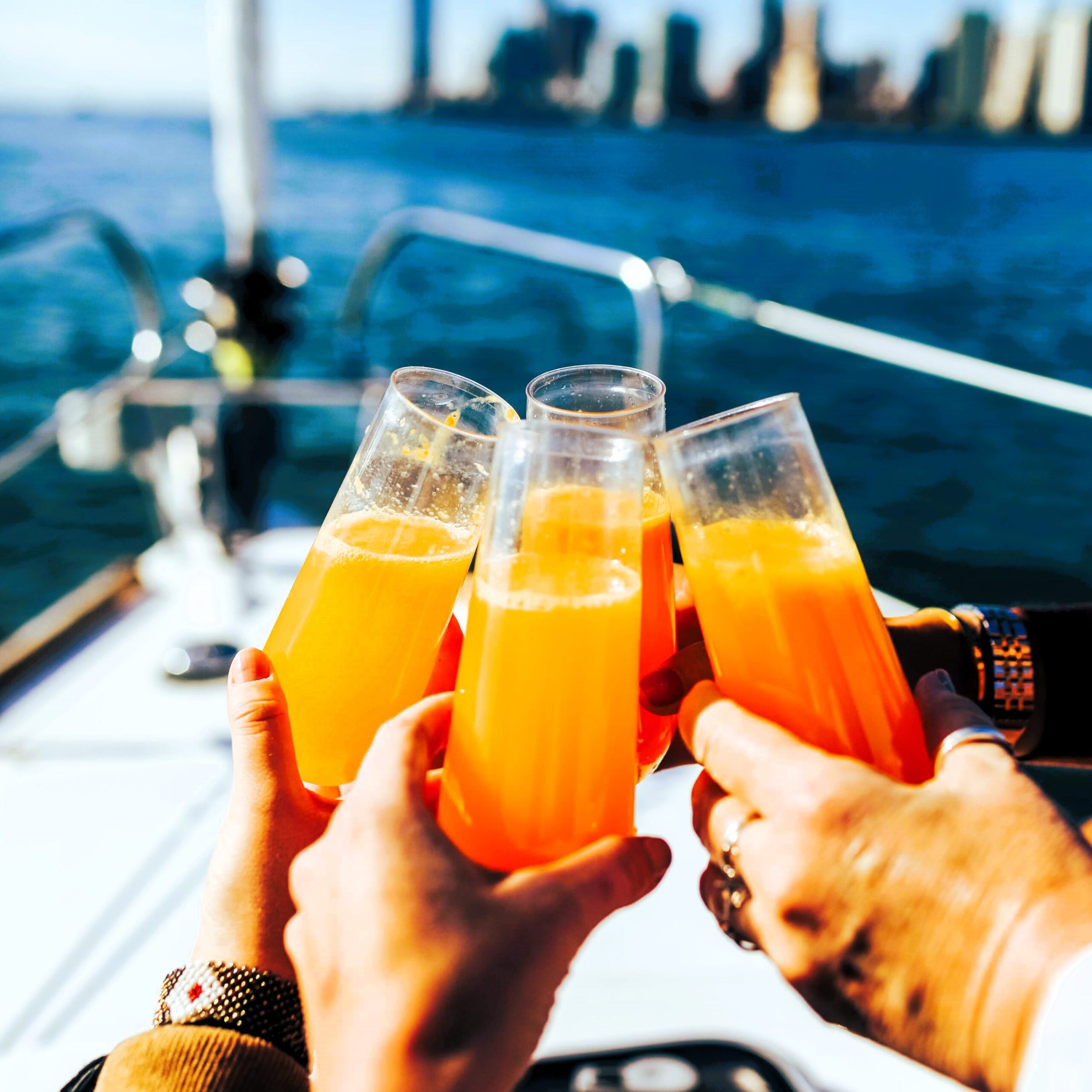 hands holding mimosas during a Sunday brunch cruise in NYC