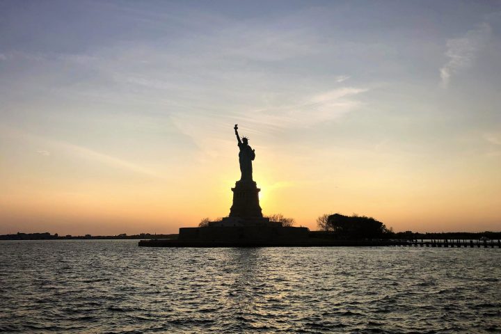 sun setting behind the statue of liberty during a private boat tour in NYC