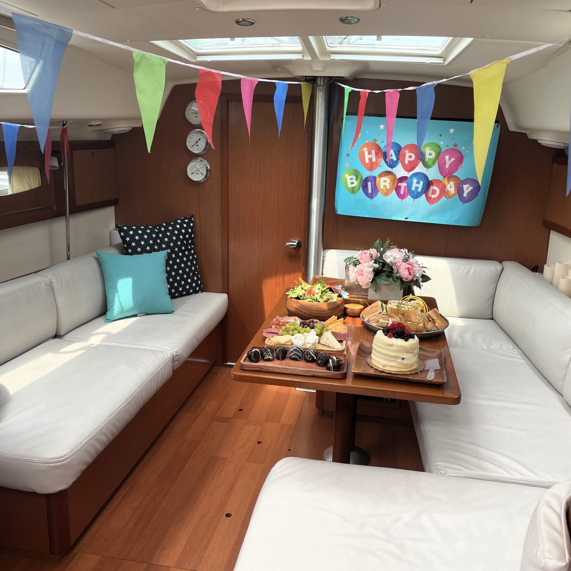 indoor cabin of a small party boat rental with wood paneling and white upholstery decorated for a small party boat rental in NYC