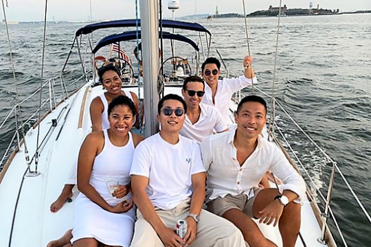 friends on the deck of a boat while private sailing NYC with the Statue of Liberty behind them