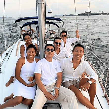 friends on the deck of a boat while private sailing NYC with the Statue of Liberty behind them