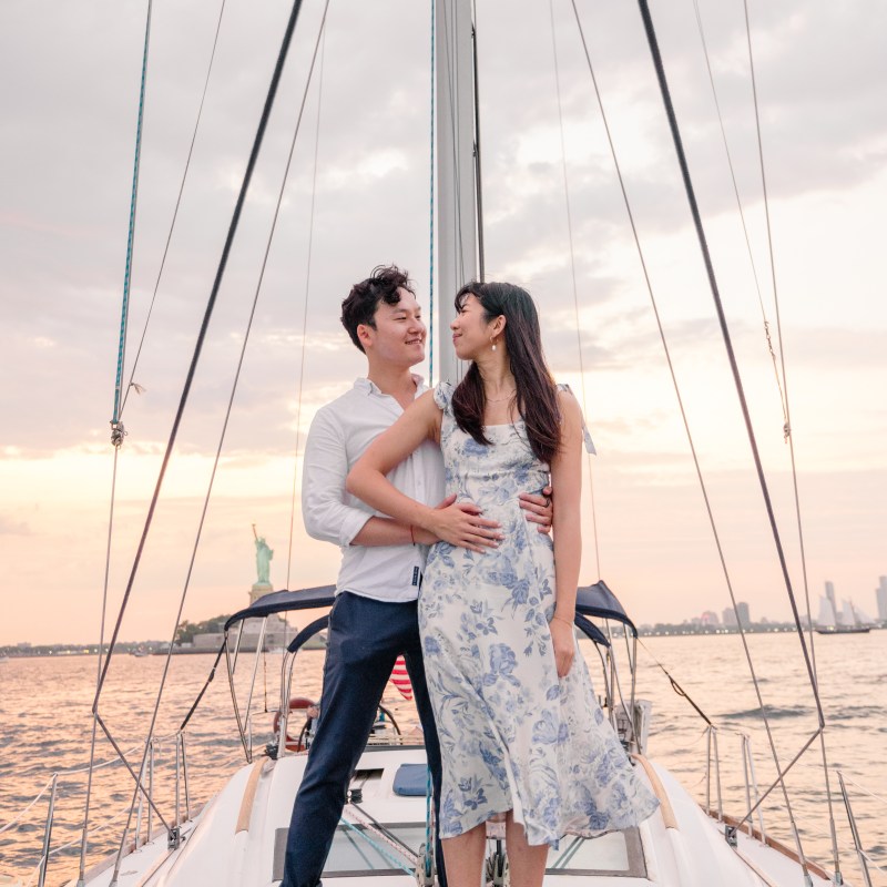 couple standing on the deck of a boat during a Statue of Liberty proposal