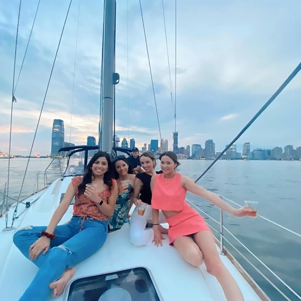 4 women on deck with the Manhattan skyline in the distance while on a sailing cruise of NYC