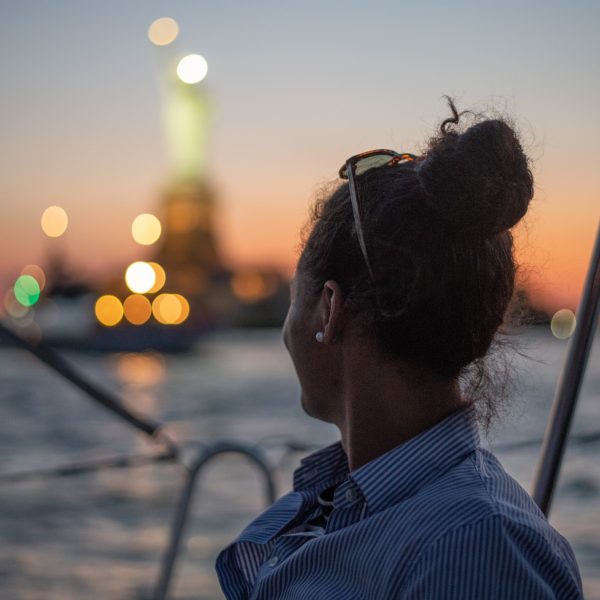 woman looking at the Statue of Liberty during a twilight cruise NYC