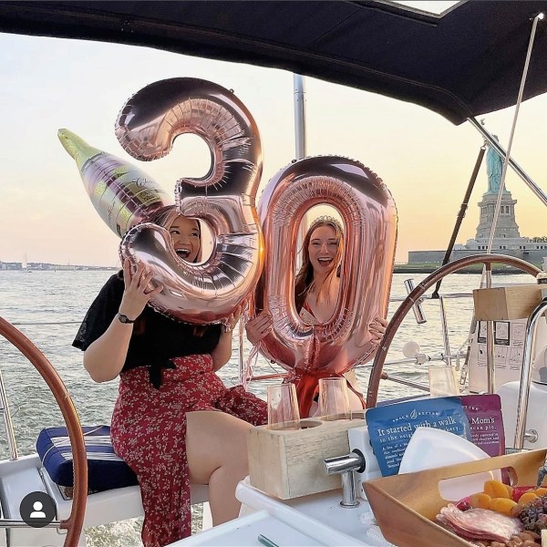 friends holding balloons on a birthday party yacht rental