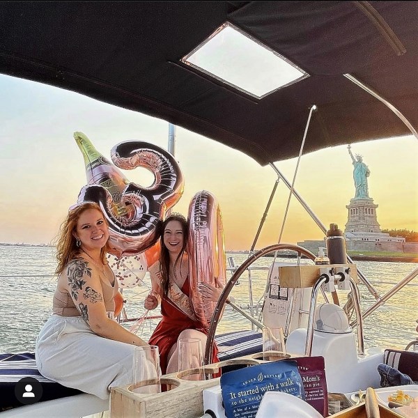 2 friends holding balloons on a party boat rental in NYC