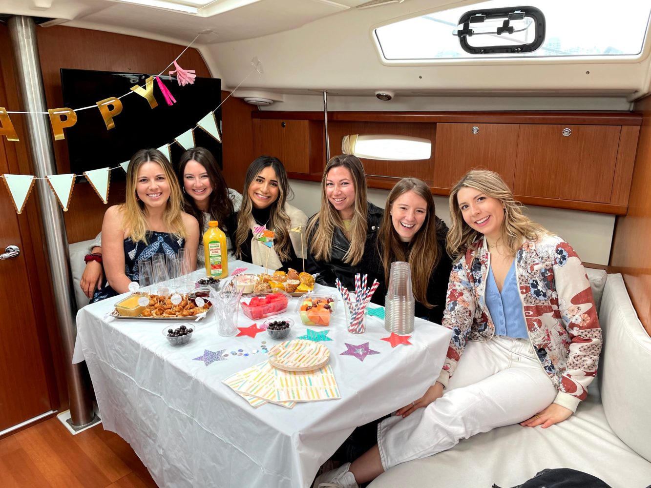 friends sitting a table on a boat with birthday decorations with a New York boat charter