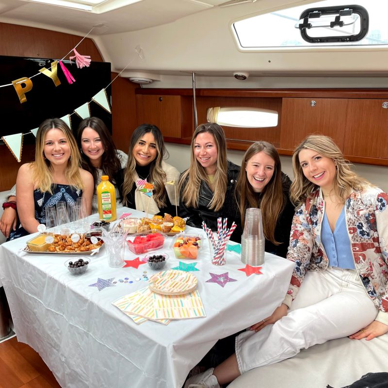 friends sitting at a table with birthday decorations on a party boat rental NYC