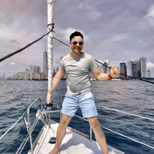 a man standing at the bow of the boat while sailing the Hudson River and the Manhattan skyline behind him