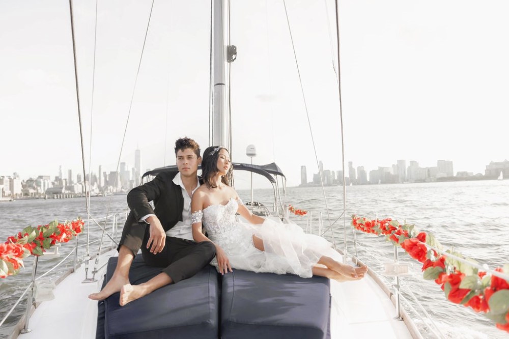 couple at the bow of a boat with red rose garlands during a romantic boat cruise NYC