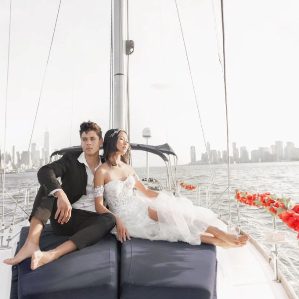 couple at the bow of a boat with red rose garlands during a romantic boat cruise NYC