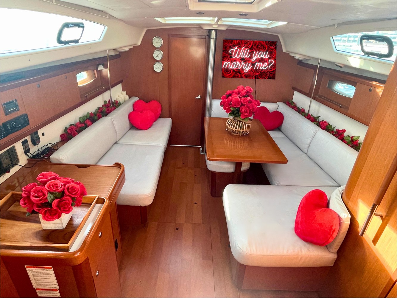 decorations for a surprise proposal on a boat with roses and garlands and the will you marry me sign