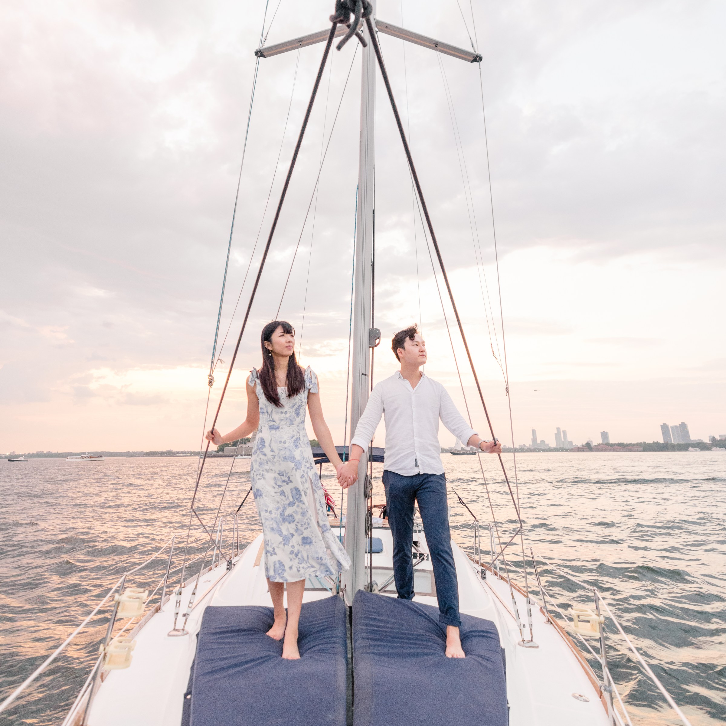 man and woman private sailing in NYC and standing on the deck of the sailboat
