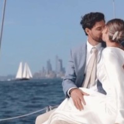 Couple kissing on a boat rental, city skyline and sailboats in background.