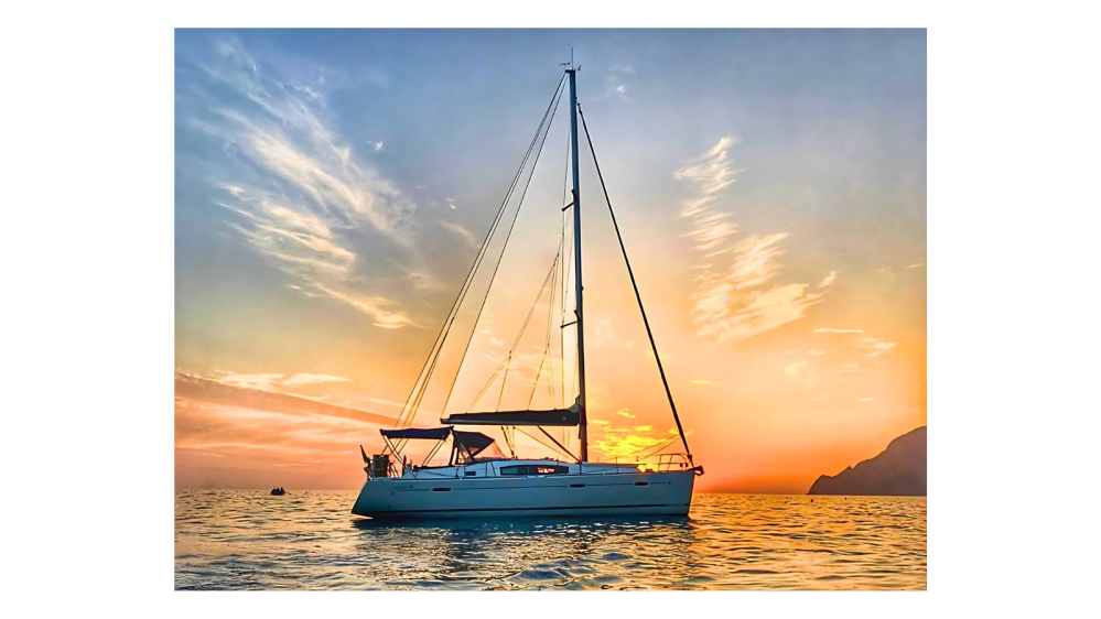 sunset sailing with orange and blue sky and white clouds behind the sailboat