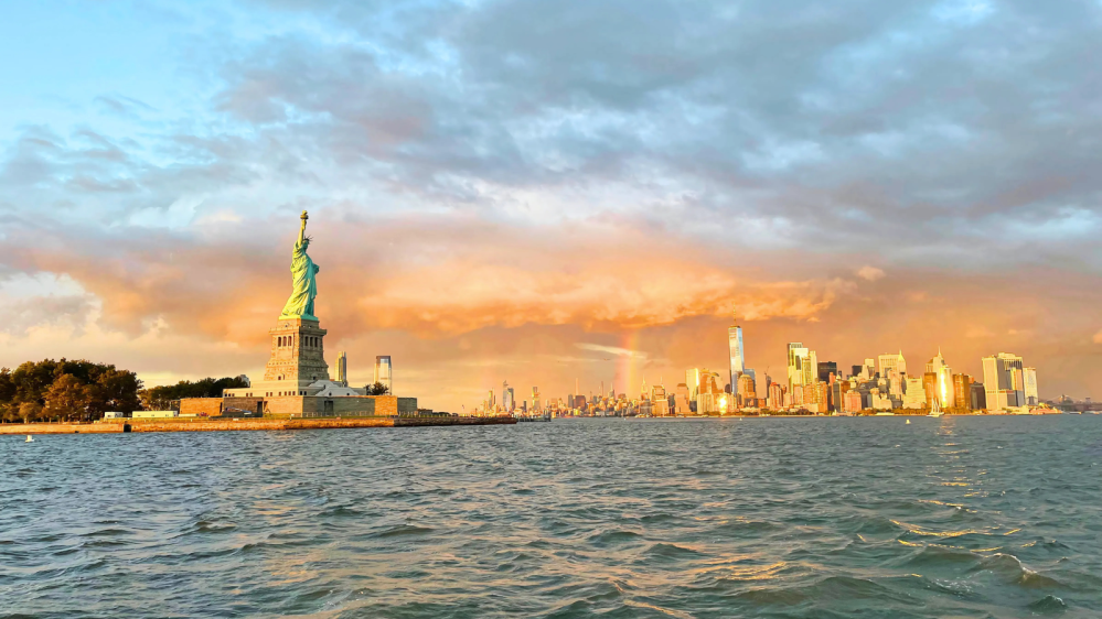 Statue of Liberty and rainbow over the Manhattan skyline during a rent a boat to scatter ashes