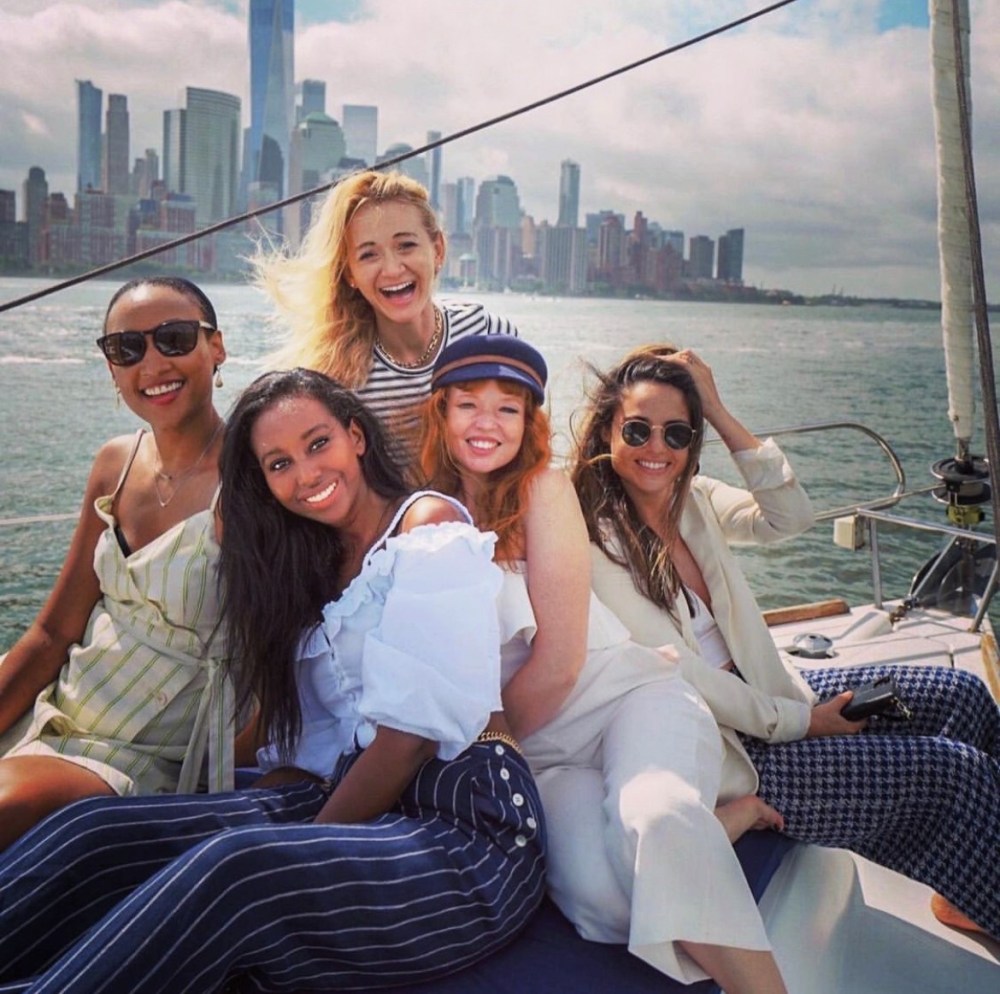 Group of friends celebrating on private boat rental NYC with 6 passengers with the city skyline in the background.