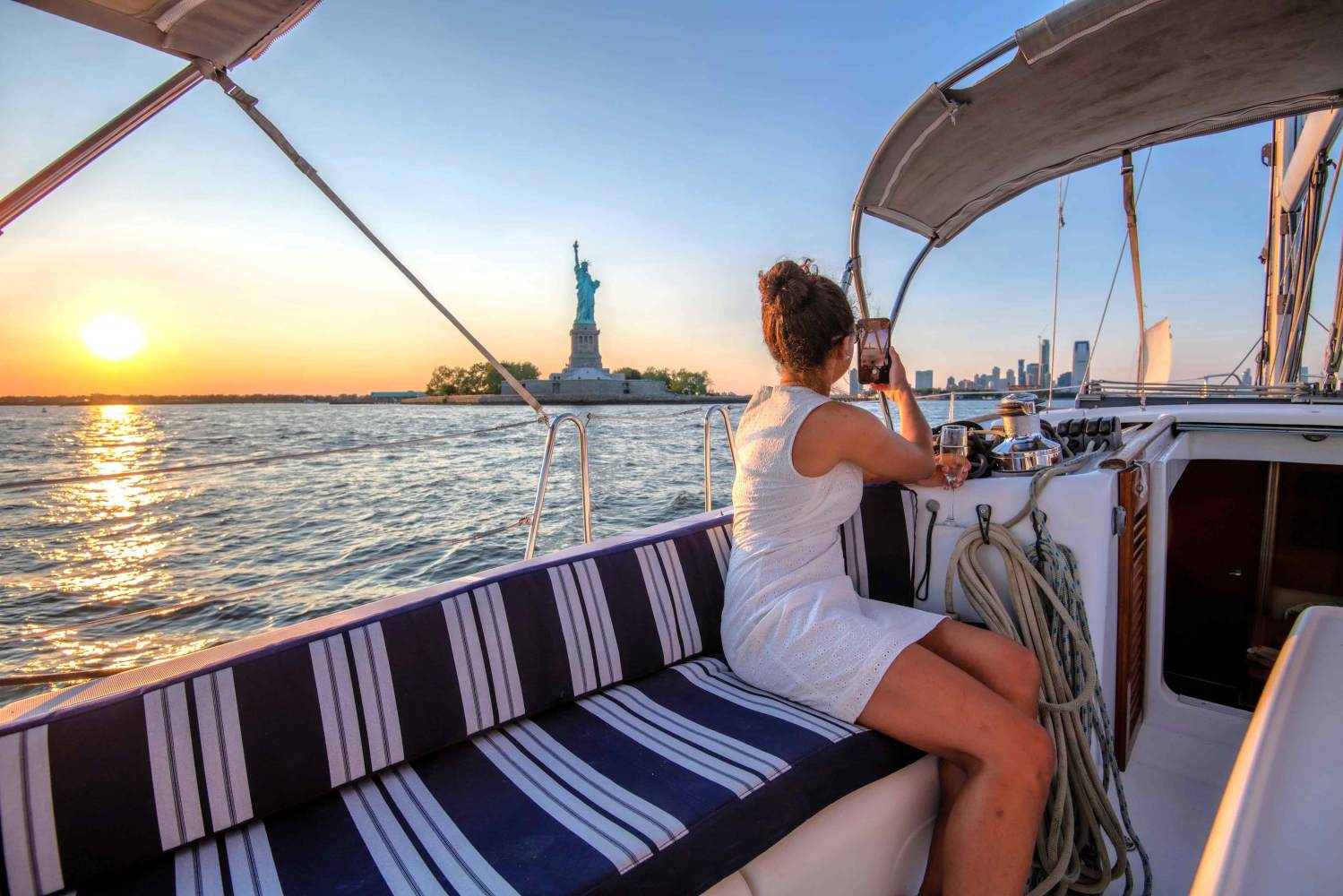 Person on a boat hire taking a photo of the Statue of Liberty at sunset in New York.