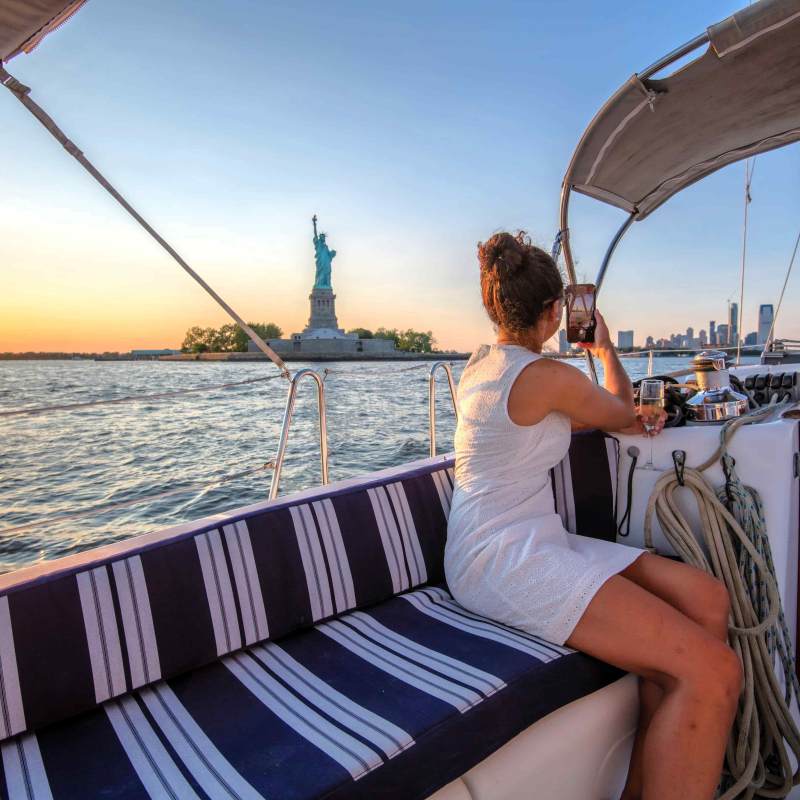 Person on a boat hire taking a photo of the Statue of Liberty at sunset in New York.