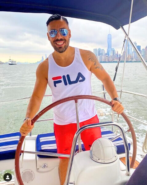Bachelor party group with a man in sunglasses on private sailboat with Manhattan skyline in the background.