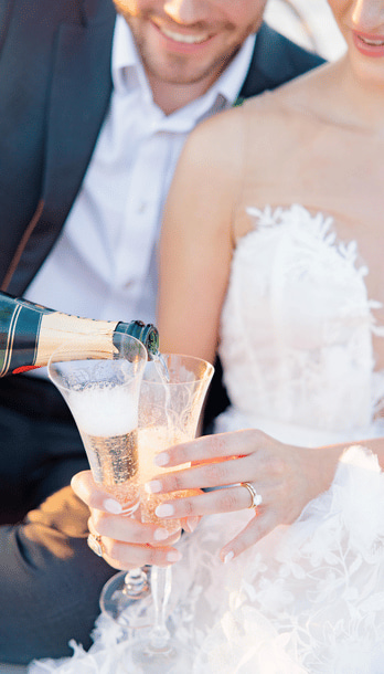 Champagne poured into glasses held by a couple in wedding attire during a yacht charter in nyc.