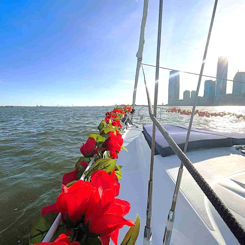 Boat decorated with red roses for a couples boat ride on a sunny day with NYC skyline in the background.