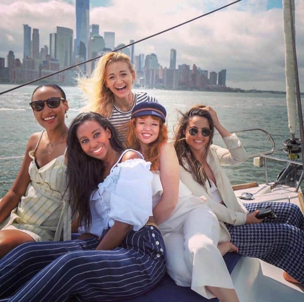 Group of friends celebrating on private boat rental NYC with 6 passengers with the city skyline in the background.