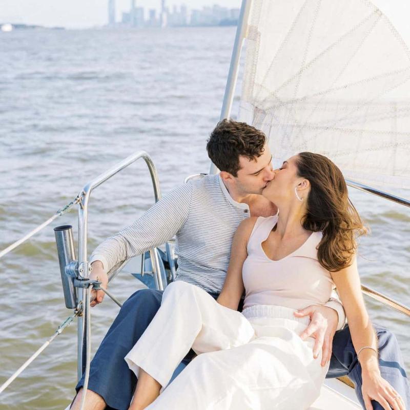 Couple kissing on a sailboat with city skyline in the background during a private boat ride in NYC for 2.