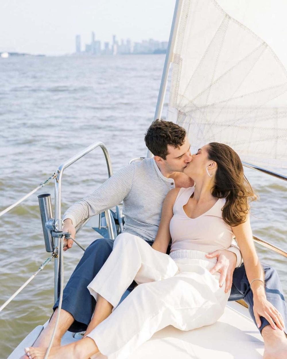 Couple kissing on a sailboat with city skyline in the background during a private boat ride in NYC for 2.