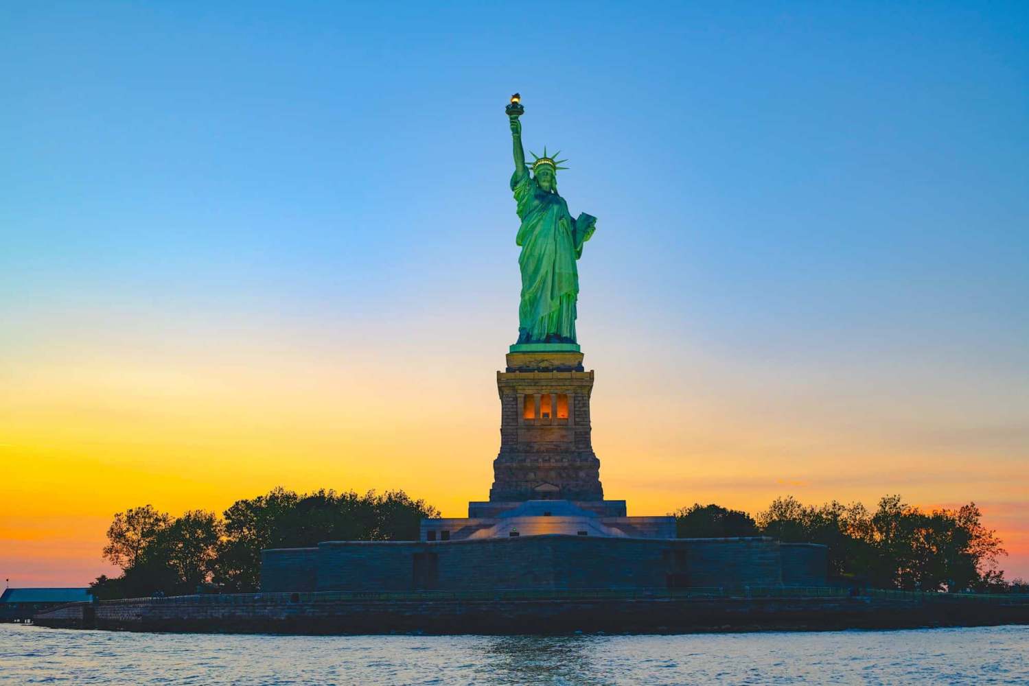 Statue of Liberty at sunset with clear sky and water in foreground during a private boat tour.