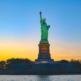 Statue of Liberty at sunset with clear sky and water in foreground during a private boat tour.